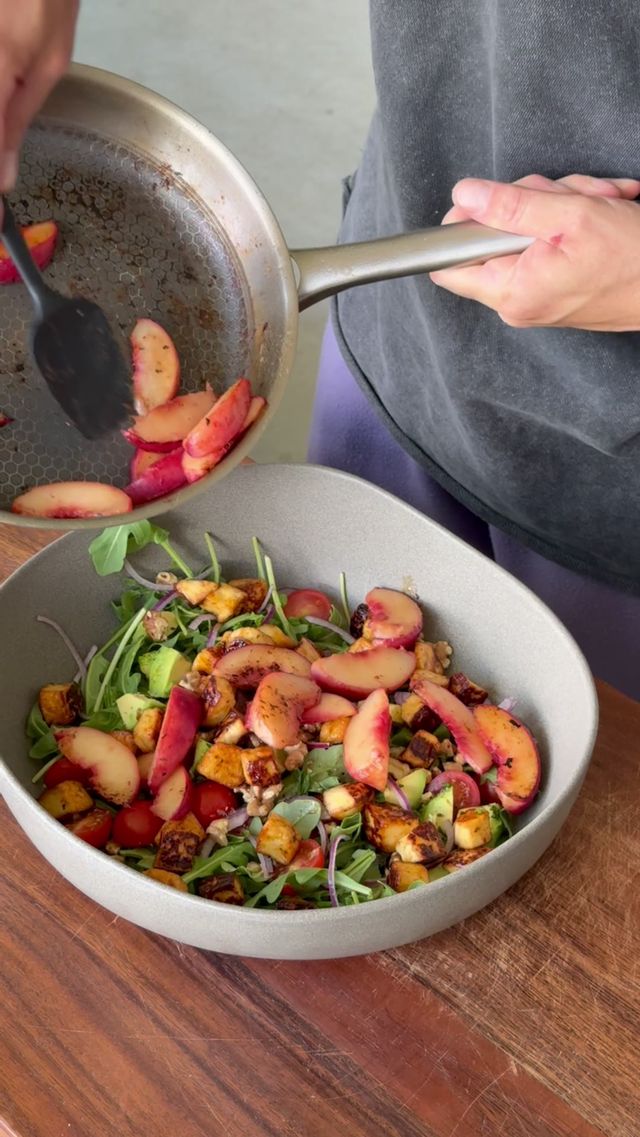 Gebratene Pfirsiche werden aus der Pfanne auf den Salat gegeben